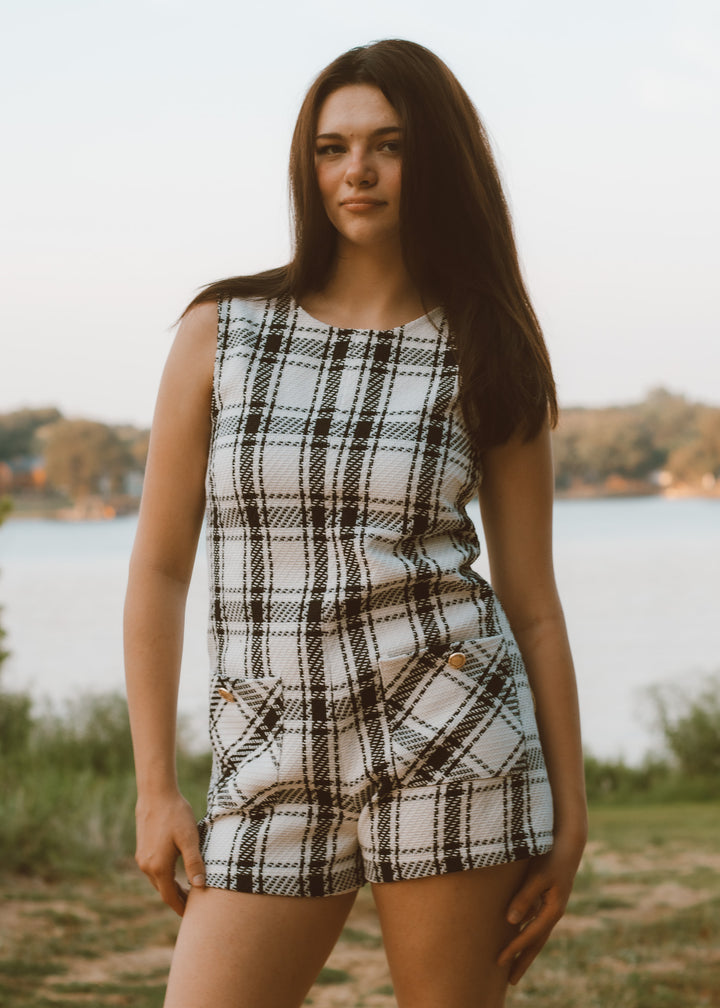Woman wearing a plaid romper standing by a lake