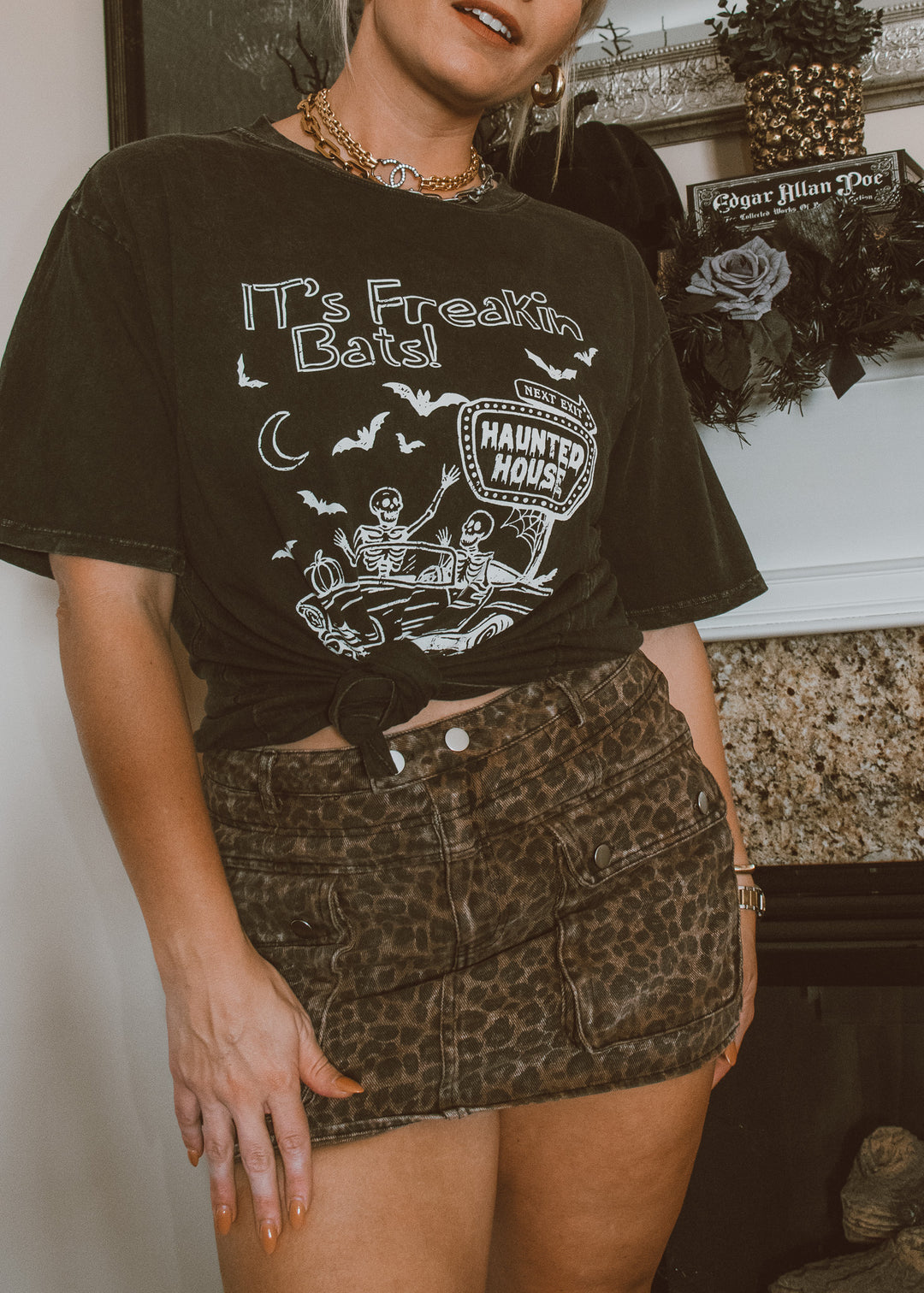 Person wearing a black t-shirt with a graphic design and leopard print skirt.