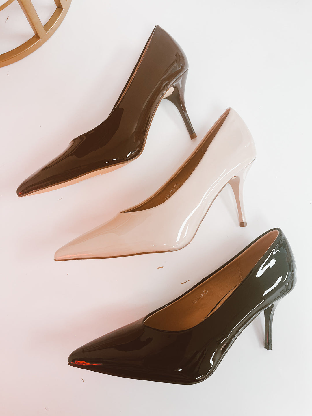 Three high-heeled shoes in brown, beige, and black on a white background