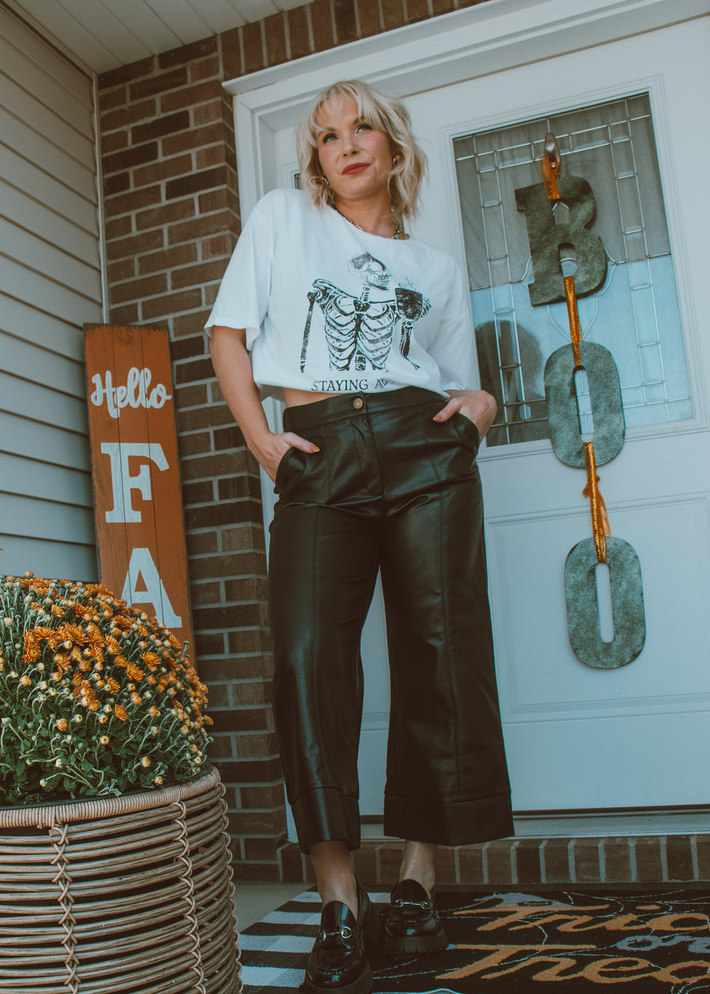 Woman standing on a porch with black leather pants.