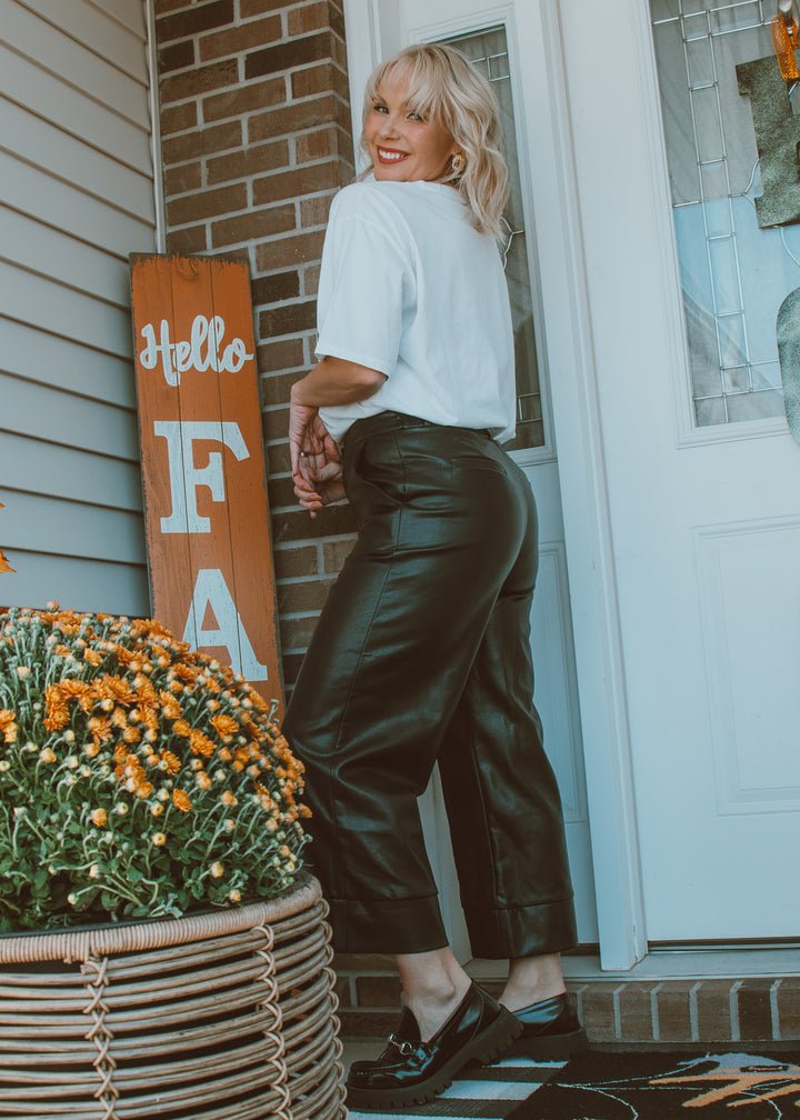 Woman standing on a porch with black leather pants.