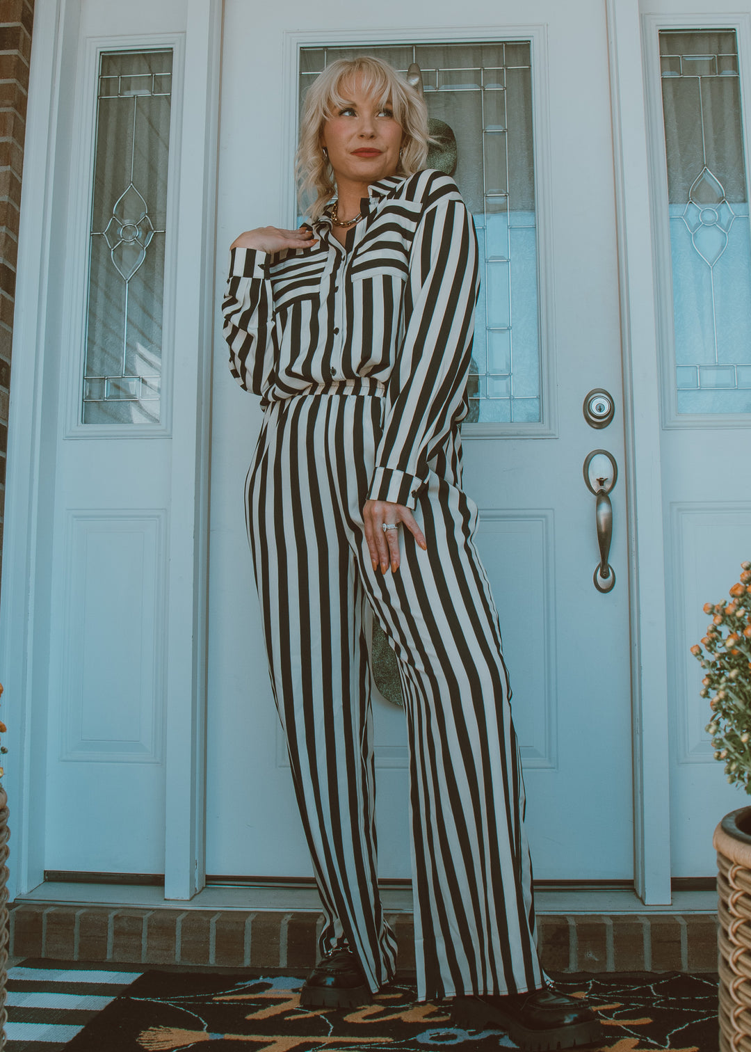 Woman in a black and white striped outfit standing in front of a door.