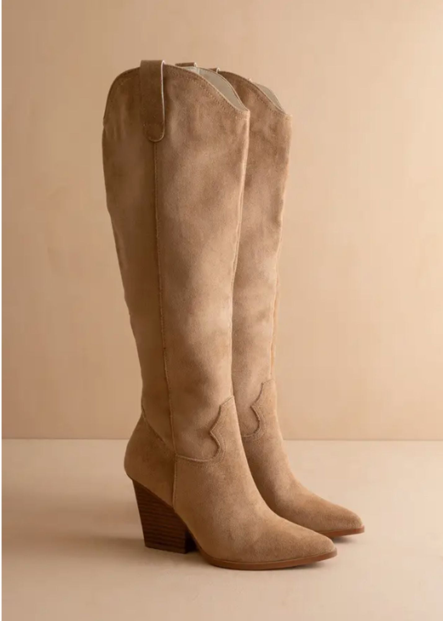Pair of beige knee-high boots on a beige background