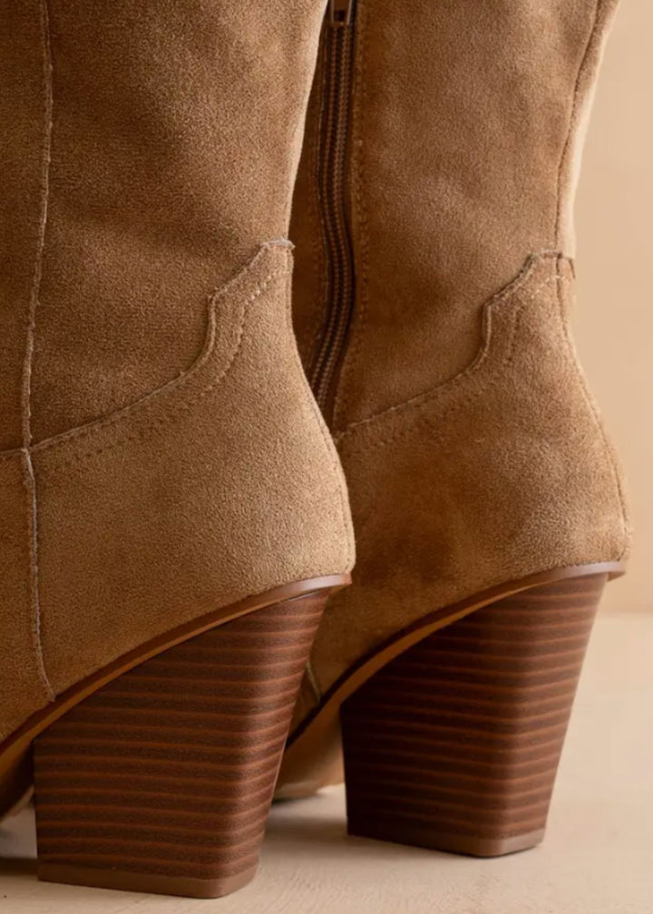 Close-up of brown suede boots with a beige background