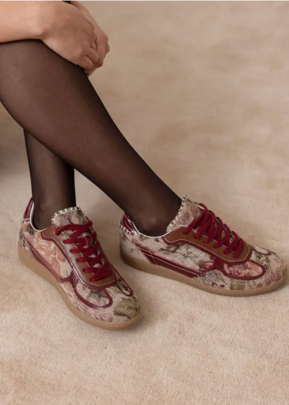 Floral sneakers worn with black tights on a beige background