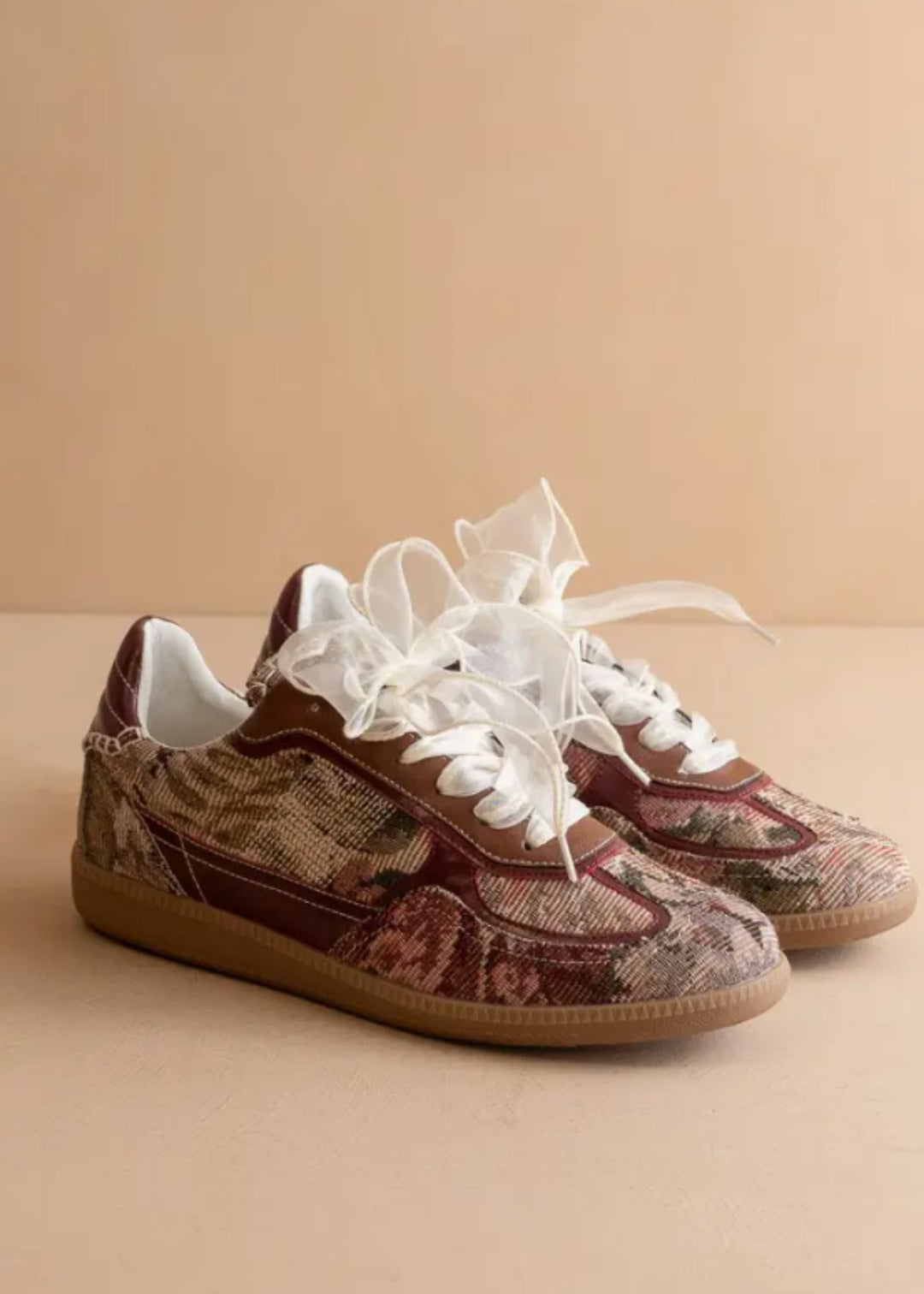 Pair of patterned sneakers with white laces on a beige background