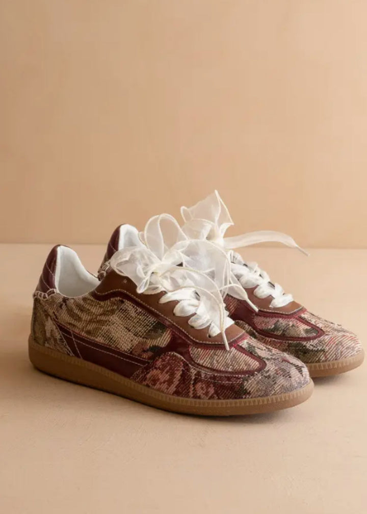 Pair of patterned sneakers with white laces on a beige background