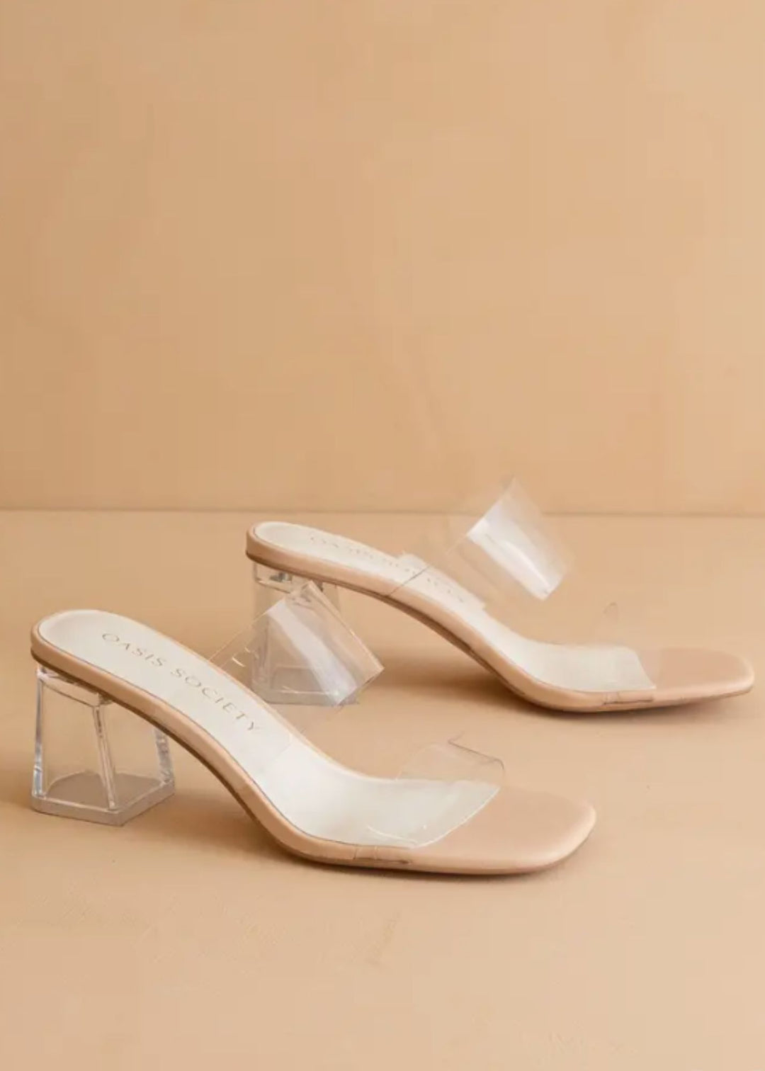 Beige high-heeled shoes with clear acrylic heels on a beige background